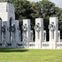 A view of the National World War II Memorial in Washington, D.C., featuring state pillars and wreaths under a sunny sky.