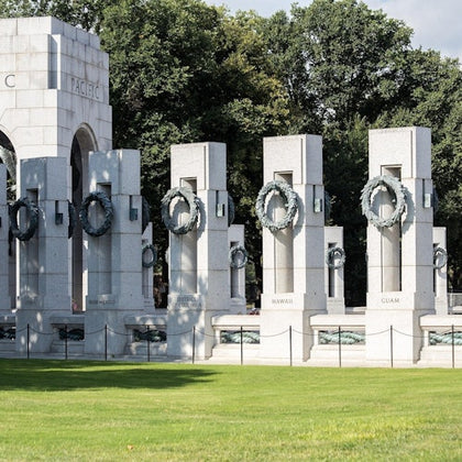 A view of the National World War II Memorial in Washington, D.C., featuring state pillars and wreaths under a sunny sky.