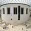 The British Museum's Great Court, featuring a large circular structure, banners on walls, and visitors on surrounding stairs.
