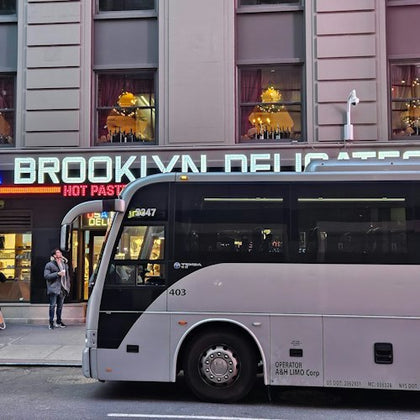 The tour departs in a luxury bus from just off Times Square , outside the Brooklyn Deli