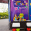 A child posing next to a LEGO DJ model at a LEGO Festival display.