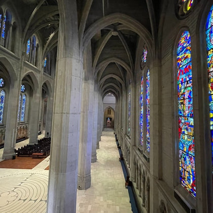 Interior of a gothic-style cathedral with high arches, stained glass windows, and a labyrinth on the floor.