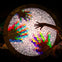 A circular table with colorful illuminated pebbles, a hand reaching over it, and a person partially visible at the bottom right.
