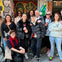 A group of people posing together in front of a graffiti-covered wall on a city street.