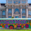 A colorful bus with 'Flower Power' painted on it, parked in front of a large historic building with ornate details.