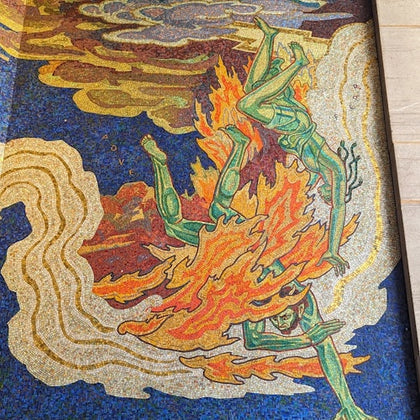A mosaic artwork depicting a green figure surrounded by orange and yellow flames against a blue and yellow background.