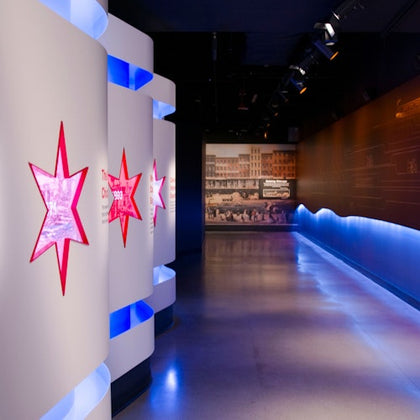 A modern museum exhibit with illuminated star-shaped displays and a backlit wall featuring historical photographs.