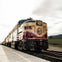 A vintage train with the number 73, labeled "Napa Valley Wine Train," on tracks next to a vineyard under a cloudy sky.