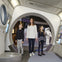 A woman and two children stand inside a space-themed exhibit with astronaut displays and interactive panels on the walls.
