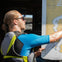 Person with sunglasses and a wetsuit, pointing to a map. The map features water bodies and landforms.