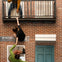 Three people appear to be climbing and hanging from a fake brick wall with a balcony, creating an illusion of danger.