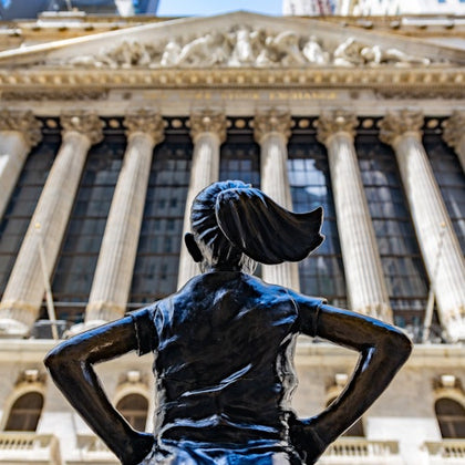 An inspiring image of the Fearless Girl Statue standing boldly before the New York Stock Exchange.