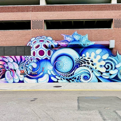 A vibrant mural featuring oceanic themes, with swirling patterns, coral, and sea life in shades of blue, purple, and white.