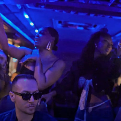 People dance and enjoy themselves under blue lighting in a dimly lit party environment.