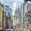 Urban street scene in Chinatown with colorful storefronts and skyscrapers in the background under a cloudy sky.