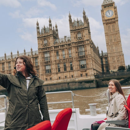 Two people on a boat ride on the Thames River with the Palace of Westminster and Big Ben visible in the background.