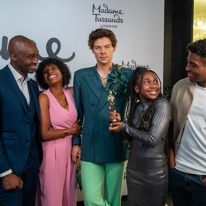 Four people pose smiling around a wax figure at Madame Tussauds London.
