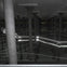An underground structure with rows of concrete columns and glowing light lines reflecting on water.