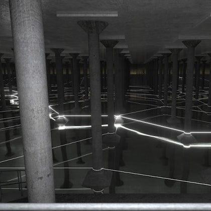An underground structure with rows of concrete columns and glowing light lines reflecting on water.