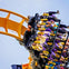 People on a roller coaster at Six Flags, with hands up in excitement, descending a track with blue sides.