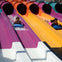 Two people sliding down colorful water slides on blue mats at a water park.