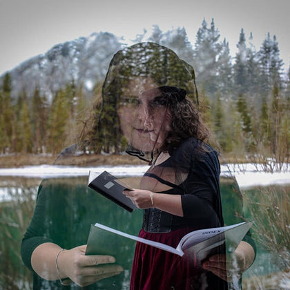 A woman, superimposed with a forest background, reads a book, holding another. Snowy trees and a lake appear behind her.
