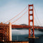 The Golden Gate Bridge spanning over water, with fog partially covering the background and clear skies above.