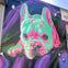 A colorful mural of a French Bulldog painted on a brick wall, featuring vibrant pink and green hues against a purple background.