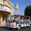 A group of people riding a tour tram in front of a Warner Bros. Studio building and water tower on a sunny day.
