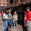 A group of people standing and talking on a sunny street in front of a shop with an awning labeled "Ladies & Gents."
