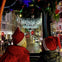 Two people in red Santa hats look out at a city street adorned with festive holiday lights.