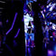 A mirrored, futuristic space with purple lighting, showing people exploring and interacting with reflective surfaces.
