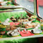 A festive table set with a tiered tray of holiday-themed treats, cups, and decorations in a vibrant green and red theme.