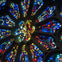 A close-up view of a stained glass rose window with colorful, symmetrical patterns illuminated by light.