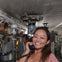 A person smiling while holding a phone receiver, standing in a submarine's interior with visible equipment and pipes.