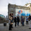 A group of people gathered in front of an old building with a large mural depicting a person swimming underwater.