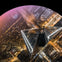 Aerial view of a lit-up city intersection at night, centered on a modern, pyramid-like skyscraper.