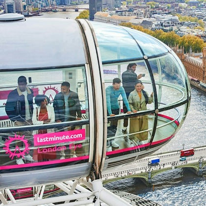 People inside a glass capsule of the London Eye, overlooking the River Thames and Westminster Bridge on a sunny day.