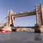 Tower Bridge over the River Thames on a clear day, with a red speedboat in the foreground.
