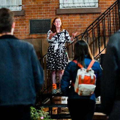 Expressive tour guide telling stories to their group outside of a historic building