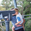 A child is being held by an adult while looking through a public binocular viewer on an outdoor observation platform.