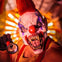A person wearing a scary clown mask with sharp teeth and holding a small bell in a vibrant, colorful setting.