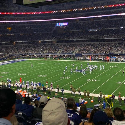 A football game in progress at a large stadium filled with spectators, with players lined up on the field's 35-yard line.