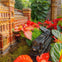 A detailed model of a train passing by a miniature building surrounded by vibrant red and green foliage.