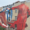 Large mural on a building depicting a person in red holding hands with another in blue and white. Graffiti is visible at the top.
