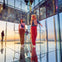 Two people standing in a mirrored observation room with a view of a cityscape during sunset.