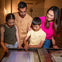Two adults and two children looking at a display table in a museum or exhibit hall.