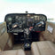 Cockpit of a small aircraft featuring dual control yokes, various instrument gauges, switches, and beige seats.