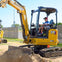 A child operates a yellow CAT excavator in a fenced outdoor area on a sunny day.
