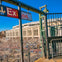Exit sign and stairs leading down from a platform with Yankee Stadium in the background under a clear blue sky.